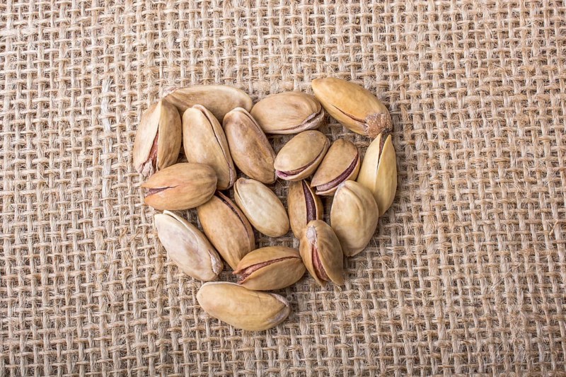 Pistachios form a heart shape on canvas background