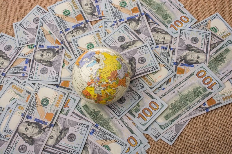 Model globe is placed on spread US dollar banknotes