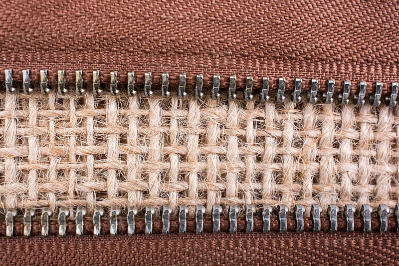 Parts of the brown color zipper on linen canvas background