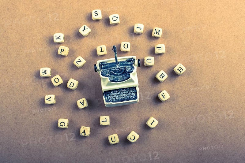 Letter cubes of made of wood around model typewritter