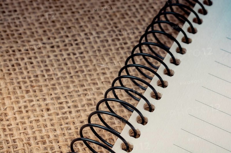 Brown color spiral notebook placed on a canvas background