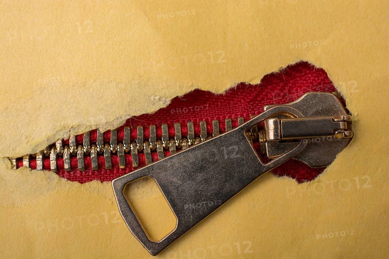 Torn paper with hole on a colorful zipper
