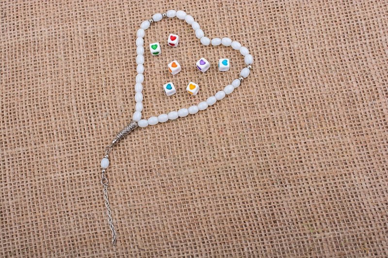 Heart shaped cubes in hand by inside a praying beads