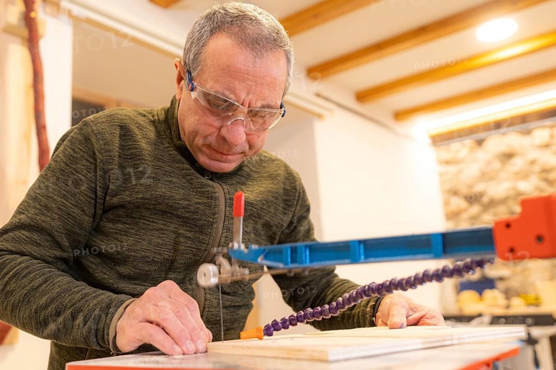 Low angle view close-up of a concentrated carpenter cutting a piece of wood in workshop