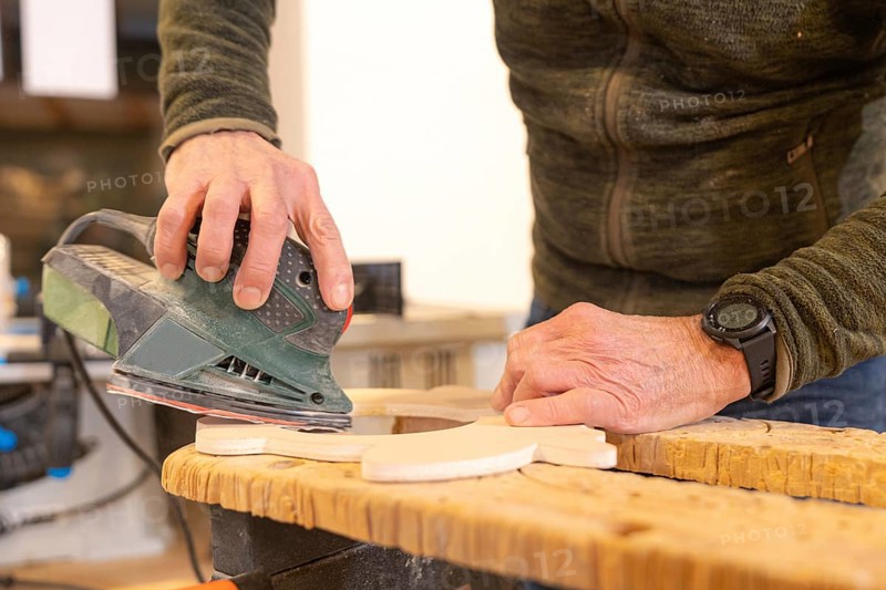 Close-up of a carpenter polishing a hole in a piece of wood using an electric tool