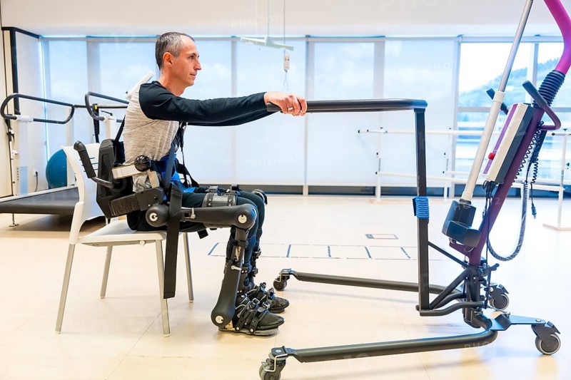 Mechanical exoskeleton. Disabled person with robotic skeleton in rehabilitation trying to get up alone