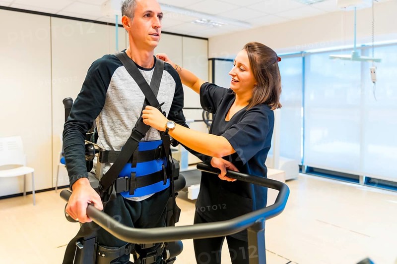 Mechanical exoskeleton. Female physiotherapy medical assistant with disabled person lifted with robotic skeleton. Futuristic rehabilitation