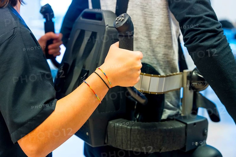 Mechanical exoskeleton. Female physiotherapy medical assistant helping disabled person with robotic skeleton to walk. Futuristic rehabilitation