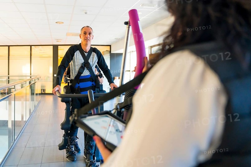 Mechanical exoskeleton. Physiotherapy woman helping disabled person to walk with robotic skeleton. Futuristic rehabilitation