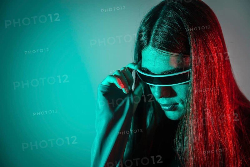 Futuristic studio portrait with neon lights of a gay man with long hair using smart goggles