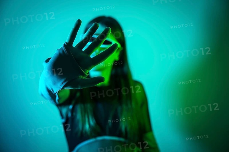Futuristic studio portrait with neon lights of a transgender man experimenting while using smart goggles