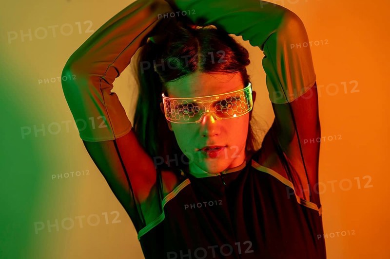 Futuristic studio portrait with neon lights of a sensual transgender person in futuristic neon space using augmented reality goggles
