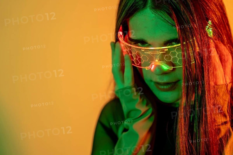 Futuristic studio portrait with neon lights of the eye contact of a transgender futuristic person using smart goggles