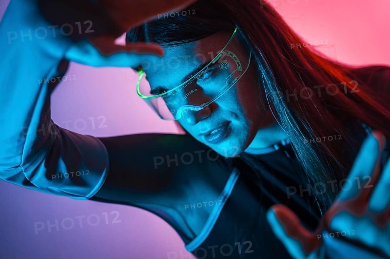 Futuristic studio portrait with neon lights of an androgynous person experimenting in the metaverse using augmented reality goggles