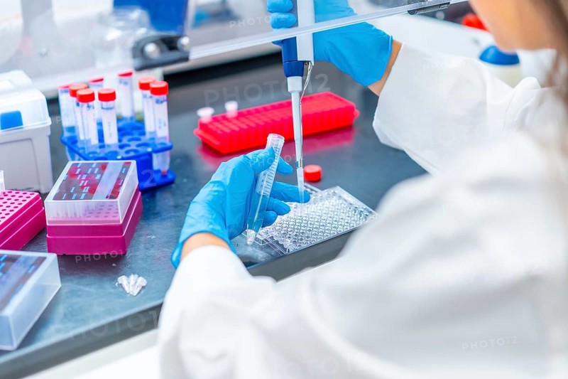 Doctor extracting samples with a pipette from a tray in a cancer research laboratory