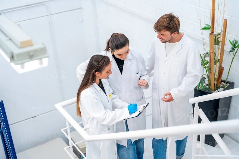Top view of three scientists talking and working standing on stairs of a cancer research laboratory