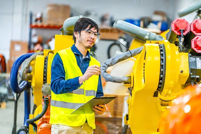 Japanese young engineer controlling the production line of robotic arms