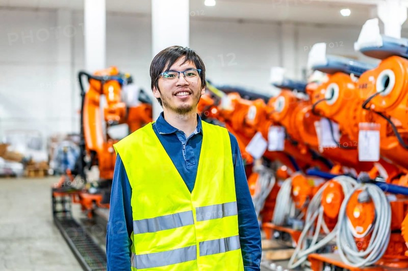 Portrait of a proud japanese chief engineer of a robotic arm production factory