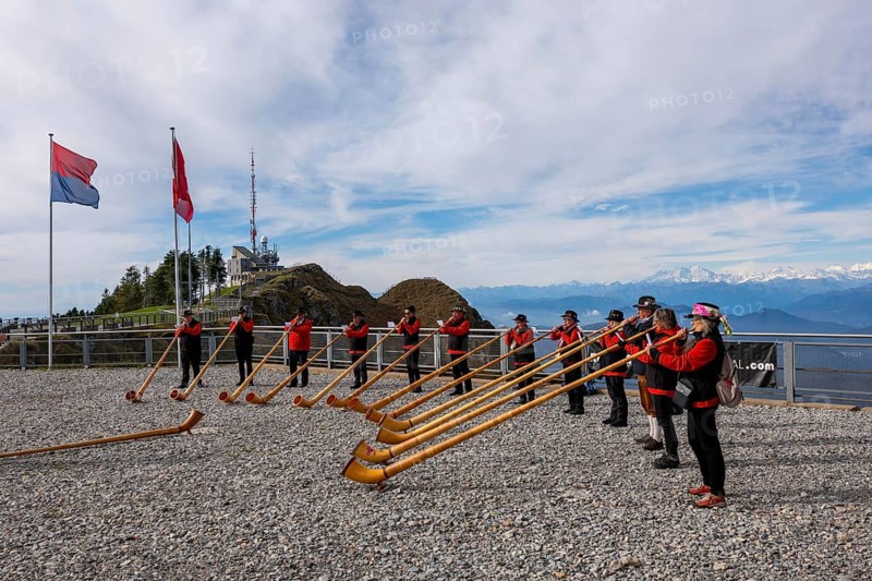 Group of Musicians Playing on Horns of the Alps with Mountainscape and View over Snow Capped Monte Rosa in a Sunny Day in Monte Generoso
