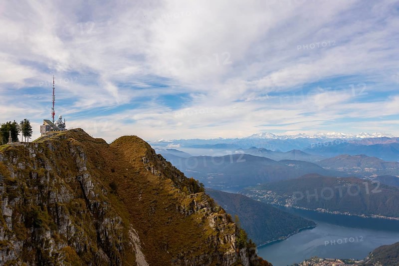 Aerial View over a Beautiful Meteorological and Communication Station on Mountain Peak and Snow Capped Monte Rosa and Lake Lugano in a Sunny Day in Monte Generoso