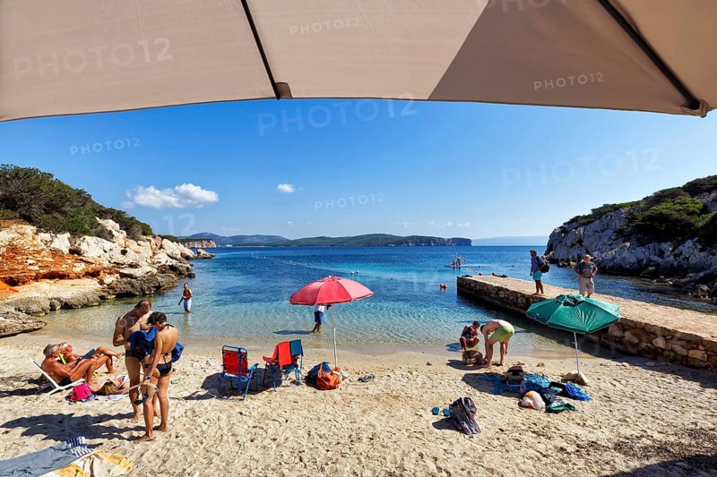 Small family beach Cala Dragunara with tourists
