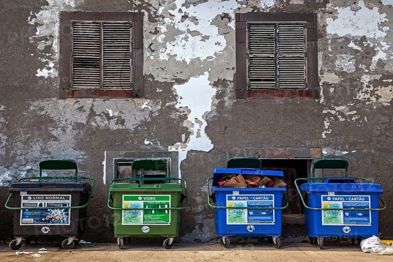 Dustbin in front of an old house wall