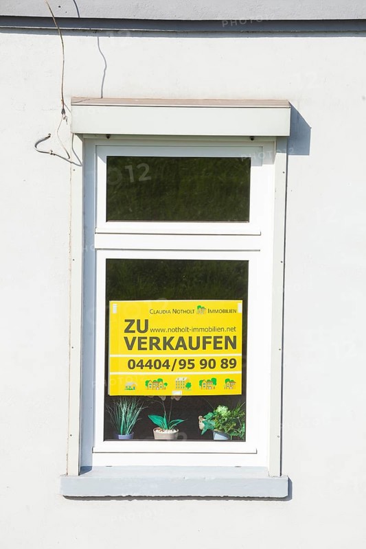 Window on an old house with sign for sale