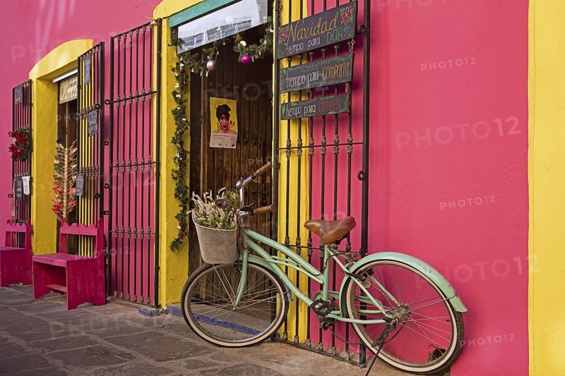 Colourful pink and yellow storefront with decorative bicycle in the city Puebla
