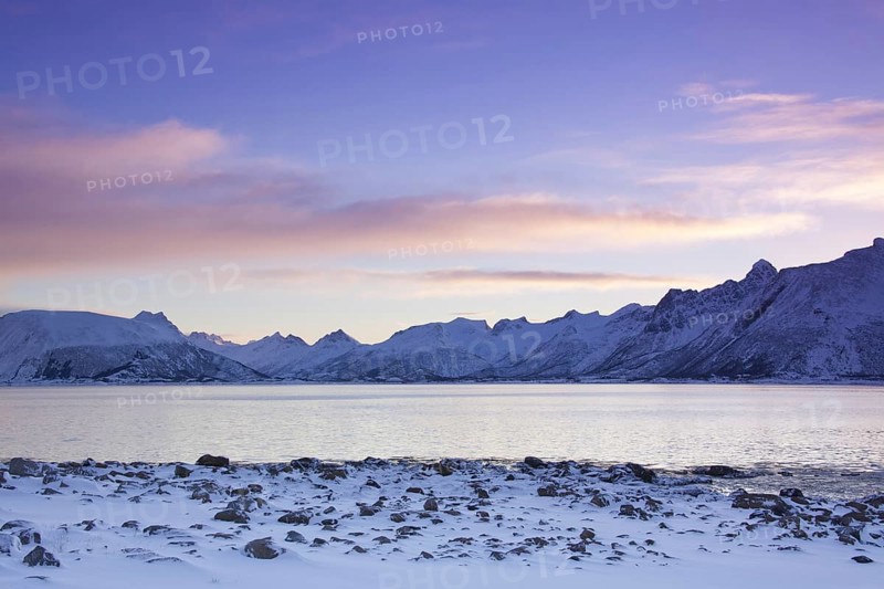 View over the Gimsoystraumen fjord and mountains in the snow in winter at sunrise