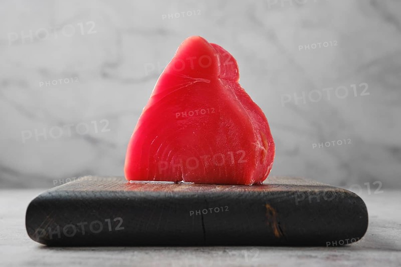 One piece of ahi tuna steak on wooden cutting board