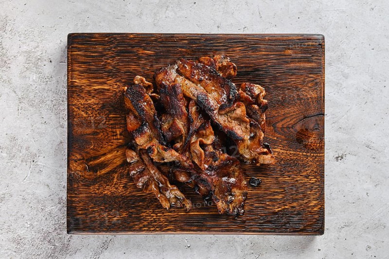 Top view of serving board with fried beef bacon strips