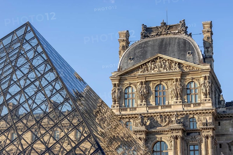 Detail of the Louvre Museum building with reflection on the glass pyramid
