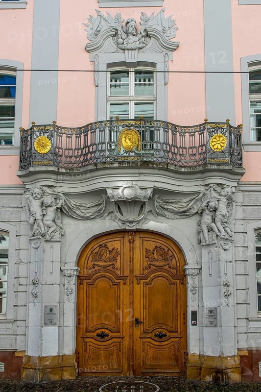 Luxurious entrance door with balcony and figures on the facade