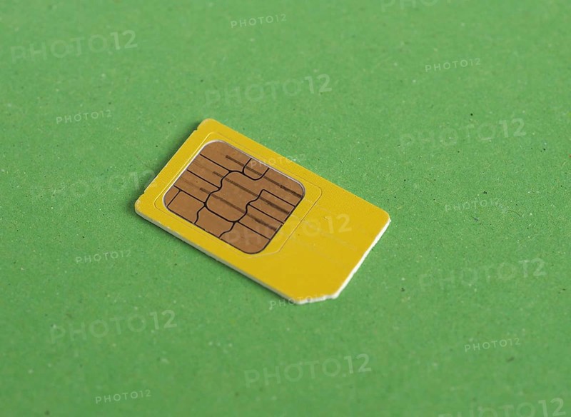 Phone sim card over green with copy space