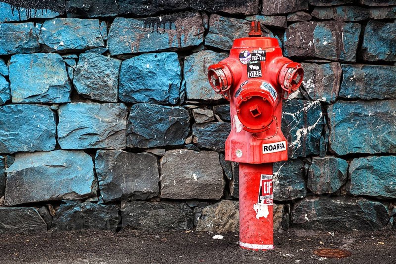 Red fire hydrant in front of a stone wall