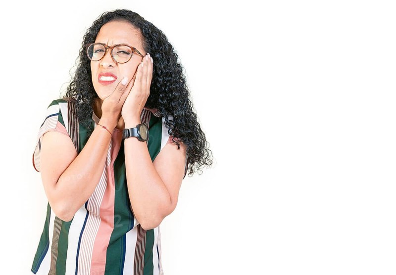 Young afro woman suffering with toothache isolated. Afro girl rubbing cheek with toothache on white background