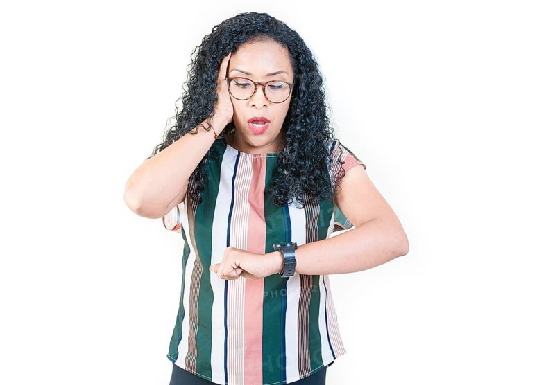 Surprised afro young woman looking at wrist watch. Worried afro girl looking at her watch isolated