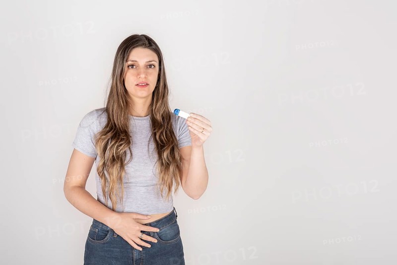 Portrait of a young blond woman holding pregnancy test feeling shocked