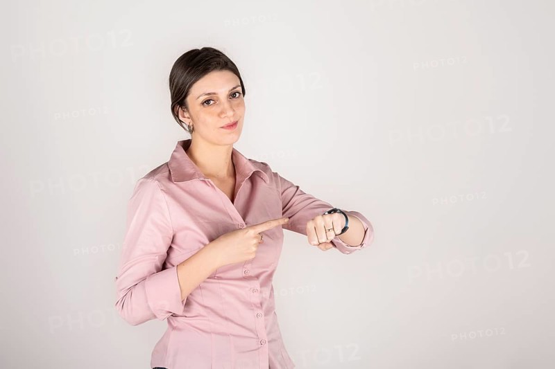 Young beautiful latin american blond business woman standing over white background in hurry pointing to watch time