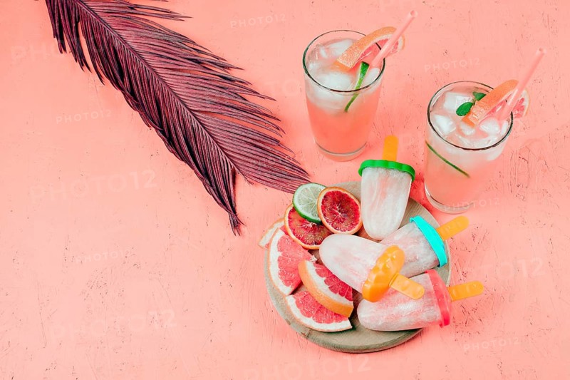 Grapefruits slices juice popsicles with leaf coral textured background