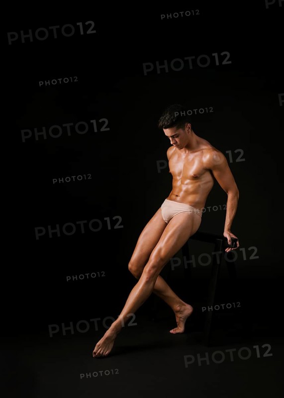Muscular dancer leaning barre