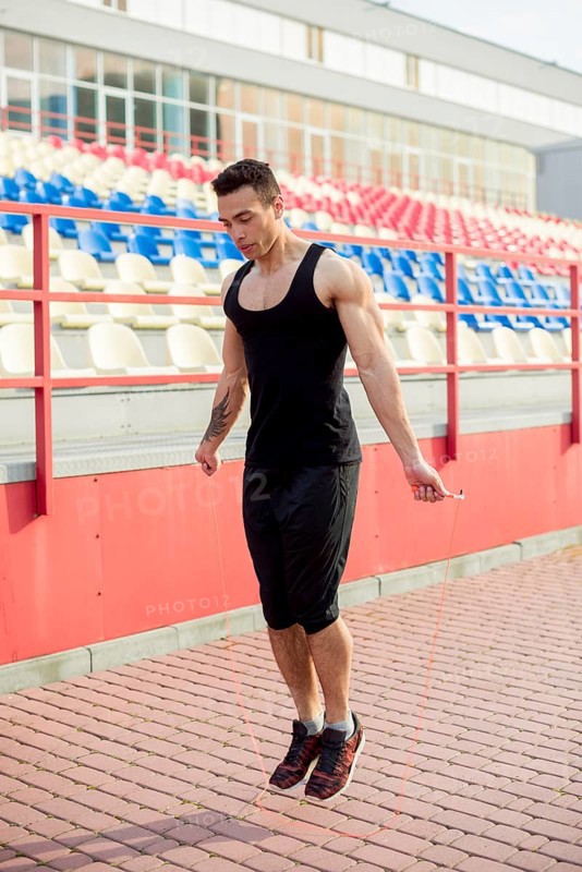 Muscular male athlete skipping front arena stadium