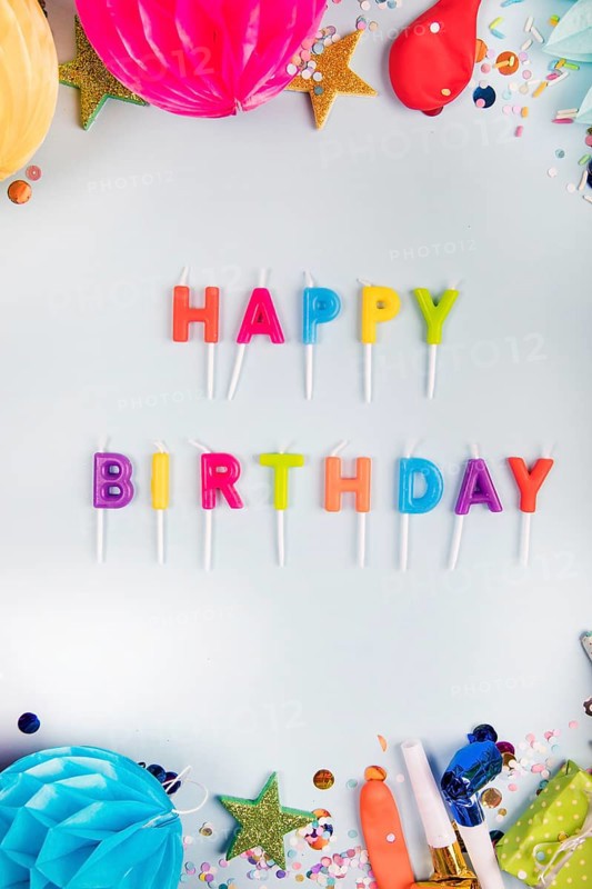 Overhead view colorful happy birthday candles with party items white backdrop