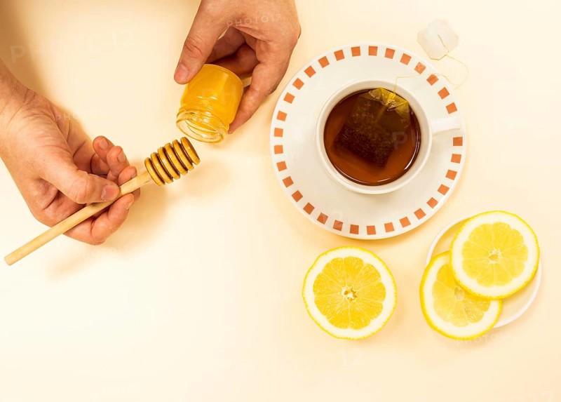 Person s hand peaking honey from jar healthy tea