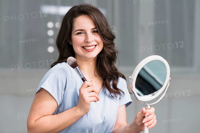 Portrait young brunette with makeup brush mirror