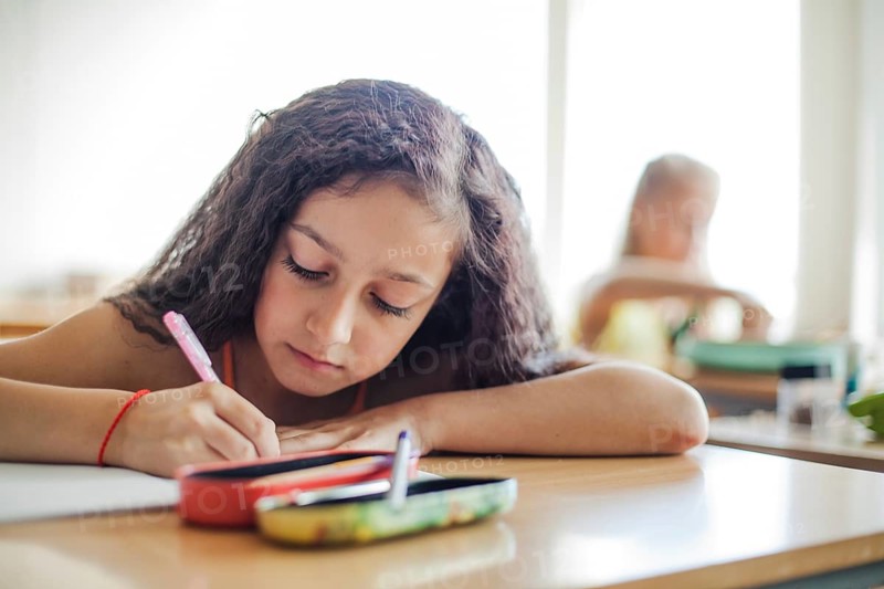 Schoolgirl sitting desk writing