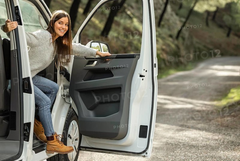 Side view smiley woman getting out car while road trip