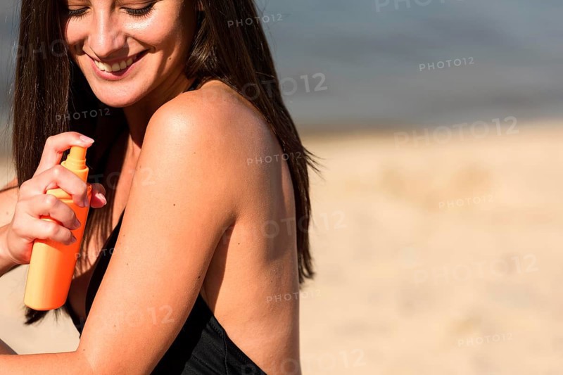 Side view woman applying sunscreen beach