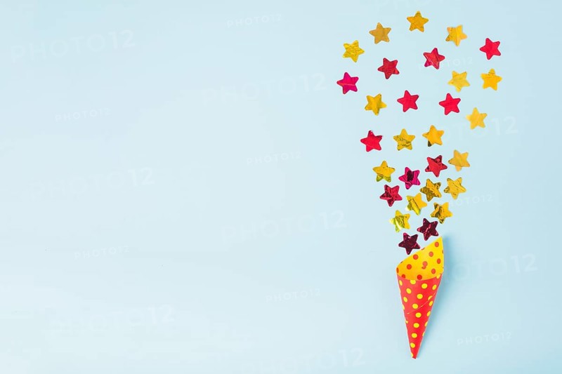 Star shape confetti coming out from paper cone with polka dot blue background