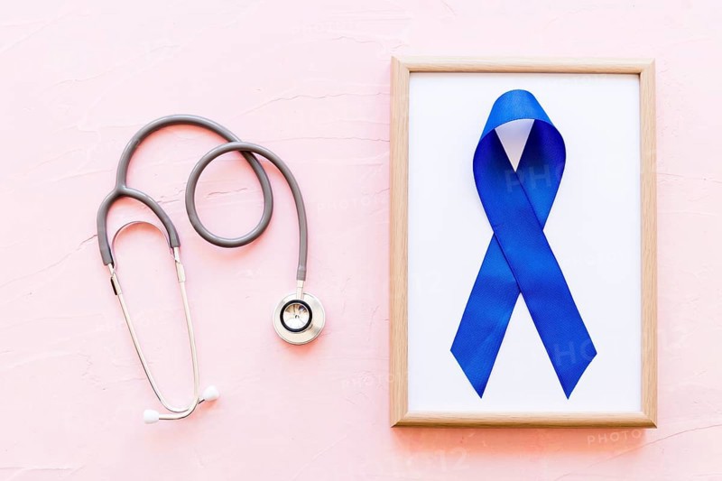 Stethoscope near wooden frame with blue awareness ribbon